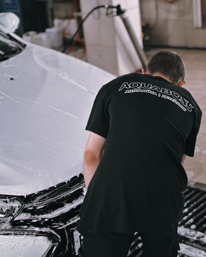 why-choose-us Professional cleaning a white car with foam in an auto garage.
